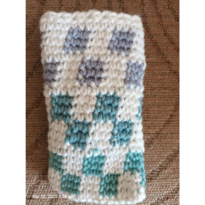 Example of tapestry crochet. A white rectangle with turquiose and light blue squares in a gridl