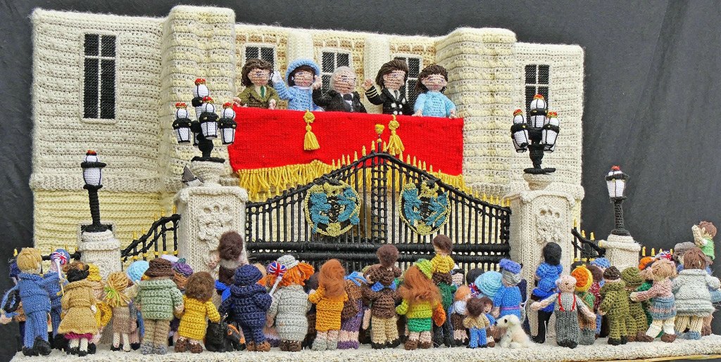 Knitted scene showing front of Buckingham Palace with the wartime Royal Family on the balcony watched by a celebrating public.