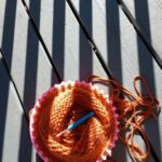 Loom knitting on wooden decking with shadows forming stripes